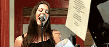 a woman singing into a microphone with the letter t visible in the corner