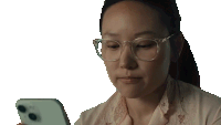 a woman wearing glasses looks at her phone