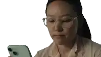 a woman wearing glasses looks at her phone