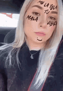 a woman is sitting in a car with a filter on her face that says mala tu vibra .