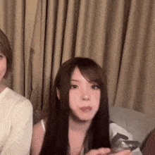 a woman with long brown hair is sitting on a couch with a man .