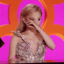 ariana grande is wearing a pink and silver dress and has a tattoo on her arm .
