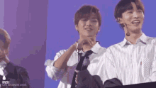a group of young men are standing next to each other on a stage and smiling .