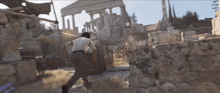 a man in a white shirt and black pants is running in front of a ruined building
