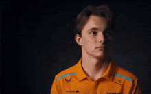 a young man wearing a mclaren shirt looks at the camera