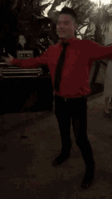 a man in a red shirt and tie is dancing
