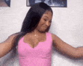 a woman in a pink tank top is standing in front of a white wall .