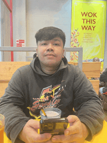 a man sits at a table in front of a wok this way sign