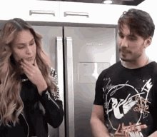 a man and a woman standing in front of a refrigerator that says brastemp on it