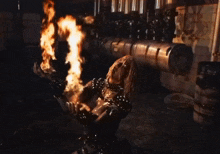 a man in a black outfit is playing a guitar with flames coming out of his mouth