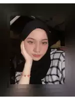 a woman wearing a black hijab and a plaid shirt holds her hand to her face