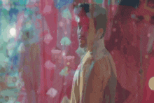 a man in a white shirt is standing in front of a pink wall with umbrellas hanging from it .