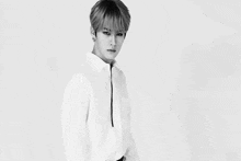 a black and white photo of a young man wearing a white shirt .