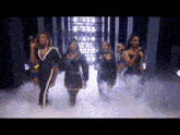 a group of women are dancing on a stage with smoke coming out of it