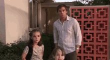 a man and two children are standing in front of a building .