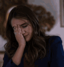 a woman with a ring on her finger covering her face with her hand