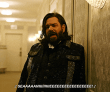 a man with long hair and a beard is wearing a sequined jacket and standing in a hallway