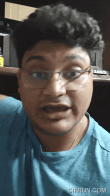 a man wearing glasses and a blue shirt has a gif run.com watermark on the bottom right