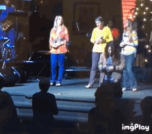 a group of people standing on a stage with a watermark that says imgplay on the bottom