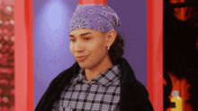 a man wearing a purple bandana and a plaid shirt is smiling