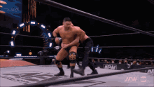 two men are wrestling in a wrestling ring with a aew logo in the background