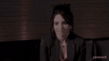 a woman in a suit is sitting on a couch with the word sure in front of her .