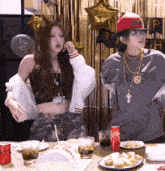 two women are standing at a table with a can of coca cola in front of them