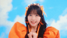 a young girl wearing an orange dress and a headband with ribbons