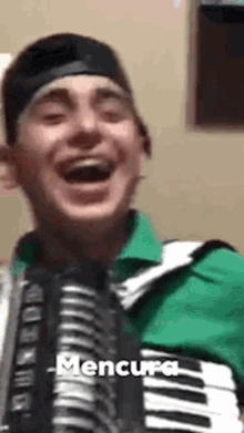 a man wearing a green shirt and a black hat is holding an accordion and laughing .