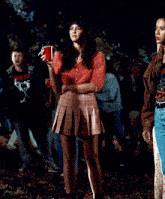 a woman smoking a cigarette while holding a red cup in her hand