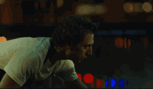 a man in a white t-shirt is crawling in the dark