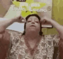 a woman is sitting on a couch with her hands on her ears .