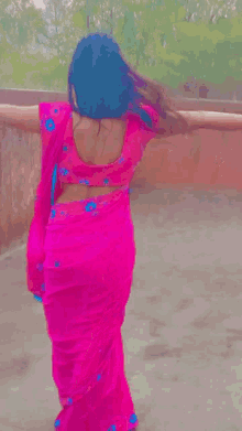a woman wearing a pink saree and a blue head scarf is dancing