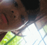 a close up of a person 's face with a blurry background of trees