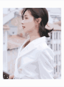 a woman wearing a white jacket is standing in front of a building .