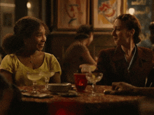 two women are sitting at a table with a martini in their hand