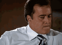 a man wearing a blue shirt and tie is making a face