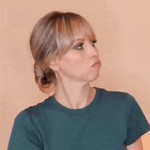 a woman with blonde hair and bangs is wearing a green shirt and making a funny face .