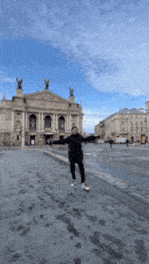 a person with their arms outstretched in front of a building