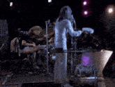 a man singing into a microphone while playing drums on stage