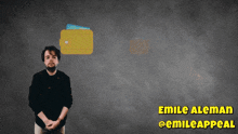 a man stands in front of a gray wall with the name emile aleman on the bottom