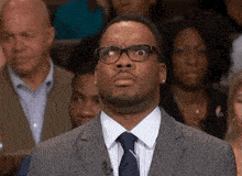 a man in a suit and tie is making a funny face in front of a crowd