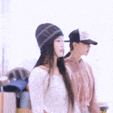 two women are standing next to each other wearing hats and sweaters .