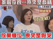 a woman wearing a white shirt with the letter k on it stands in front of a group of people