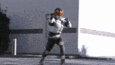 a man in a superhero costume is standing in front of a building and holding a sword .