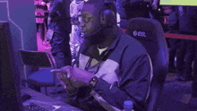 a man wearing headphones sits in front of a computer with a bottle of aquafina water next to him