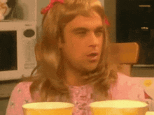 a man dressed as a girl is sitting at a table with cups