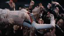 a woman in a corset is being held up by a crowd of people with their hands in the air