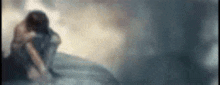 a blurred image of a woman sitting on the edge of a cliff .