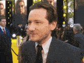 a man in a suit and tie is standing in front of a crowd